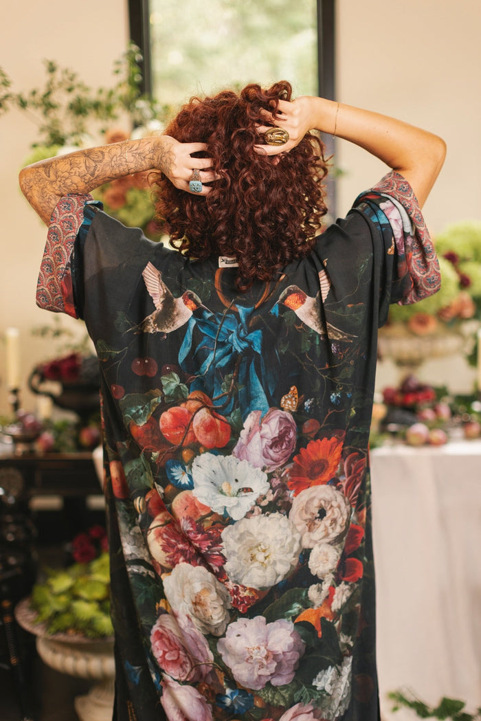 Model showcasing the Flight of Fancy Opera Robe featuring vibrant hummingbirds and historic floral paintings by Rachel Ruysch – Market of Stars.