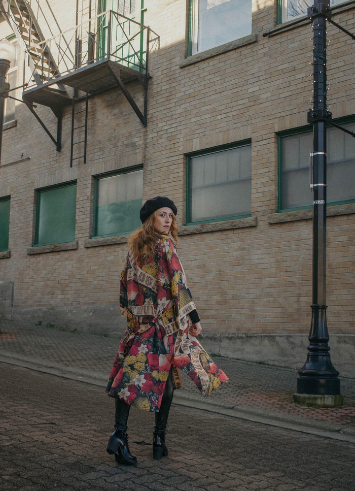 Model wearing our long, eclectic opera duster featuring vintage symbols of love, kindness, and truth in a bold archive-inspired print with removable belt – Market of Stars.