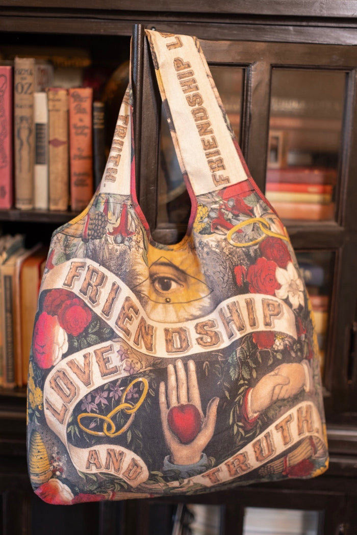 Model holding Friendship Love and Truth tote featuring historic symbols of cooperation, teamwork, eternal love, and truth from an 1880s print – Market of Stars.