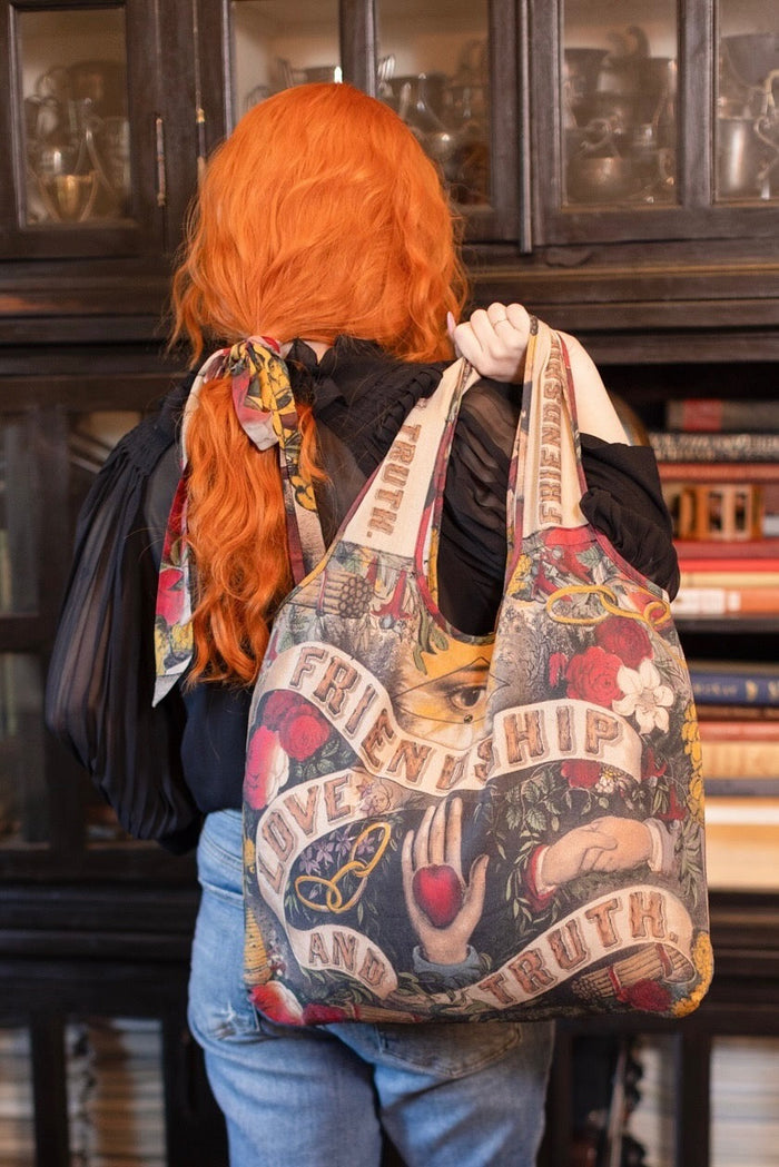 Model holding Friendship Love and Truth tote featuring historic symbols of cooperation, teamwork, eternal love, and truth from an 1880s print – Market of Stars.