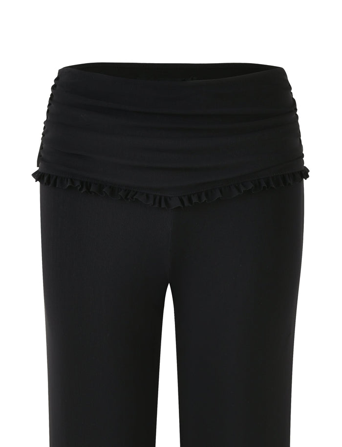 The GINNY PANT - BLACK by TIGERMIST showcases a wide, ruffled waistband and a chic, flared silhouette. The smooth and stretchy fabric effortlessly combines simple elegance with versatility, making it perfect for both casual and dressy occasions.