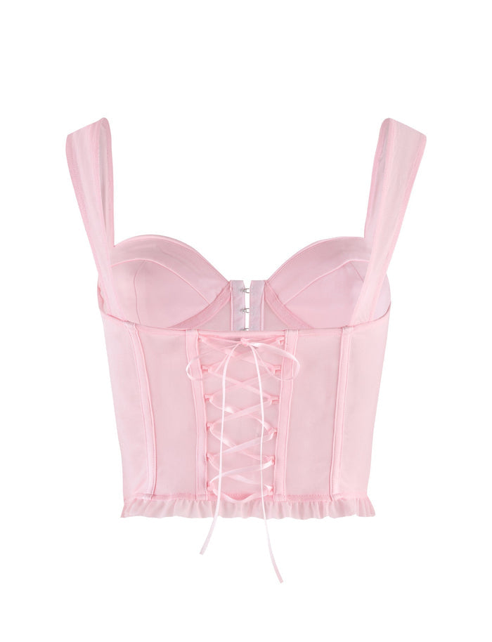 The GINNY TOP - PINK by TIGERMIST is a baby pink satin corset with wide straps, structured cups, lace-up front, and ruffled hem, designed for a fitted, feminine silhouette.