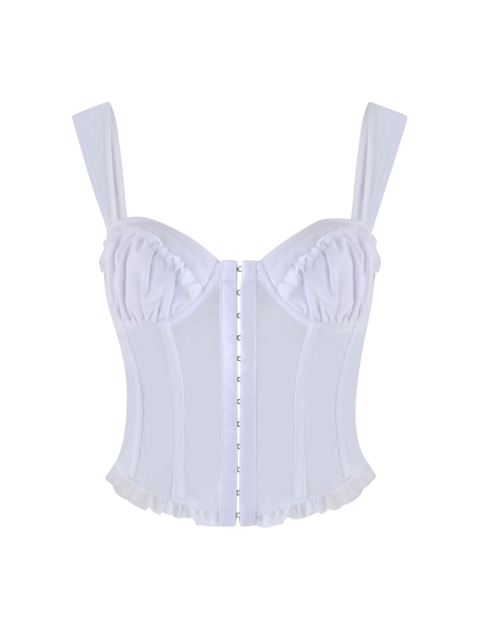 The GINNY TOP - WHITE by TIGERMIST is a corset-style top in Optic White, featuring thick straps, structured cups, vertical boning, front hook-and-eye closures, and ruffled trim along the bottom edge on a plain background.