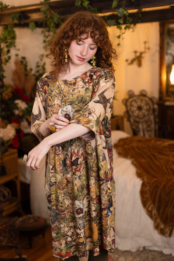 Model wearing a soft bamboo-viscose knee-length dress featuring rich 1700s botanical blooms and swallow trim - Market of Stars