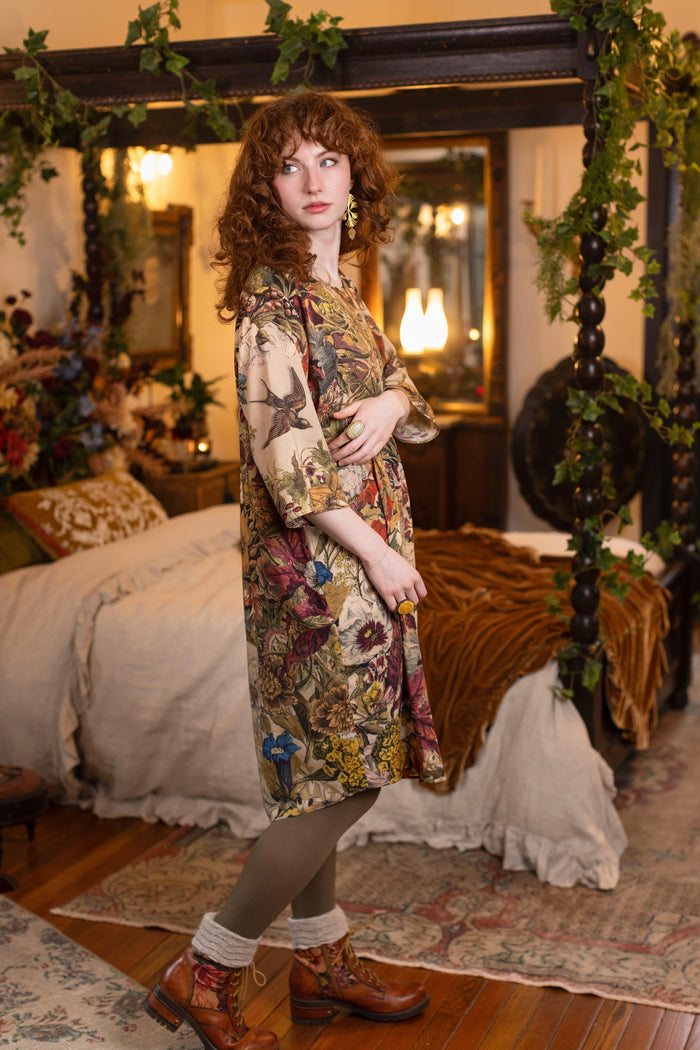 Model wearing a soft bamboo-viscose knee-length dress featuring rich 1700s botanical blooms and swallow trim - Market of Stars