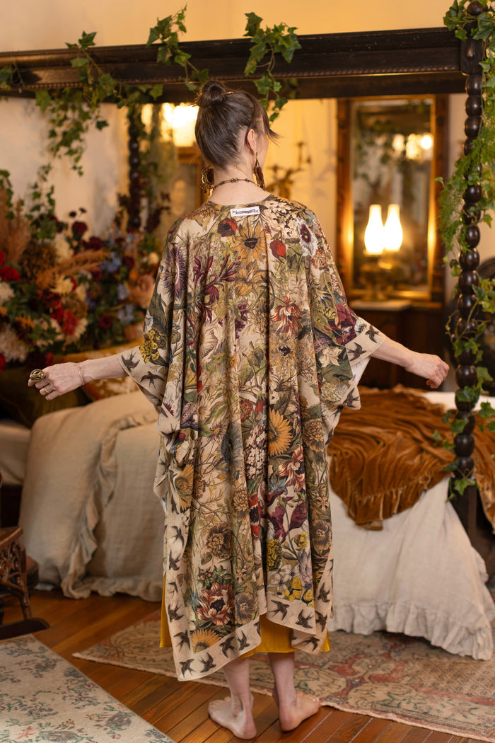 Model wearing a soft bamboo-viscose flowy duster featuring rich 1700s botanical blooms and swallow trim - Market of Stars
