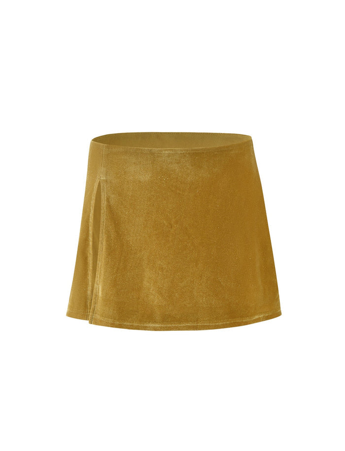 The HARLOWE SKIRT - GOLD by TIGERMIST is a mustard-yellow mini skirt featuring a slight A-line silhouette crafted from a soft, velvet-like fabric. It includes a subtle side slit on the left, adding a stylish detail to its otherwise simple design.