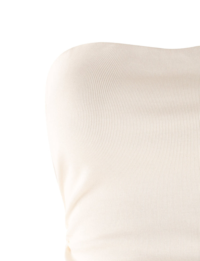 A close-up of a white and cream ribbed fabric from the HARRIETT RIB TUBE TOP by TIGERMIST. The texture of the material is visible, showing minor wrinkles and a smooth, snug fit over what appears to be a curved surface. The background is plain and white.