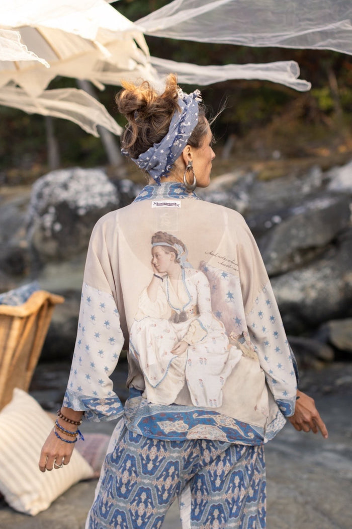 Model wearing the Head in the Clouds Opera Duster featuring Liotard’s portrait of his wife with Turkish textiles, starry sleeves, and poetic script – Market of Stars.