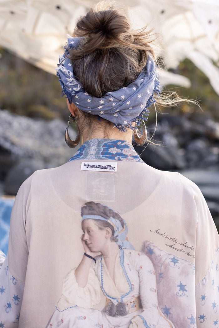 Model wearing the Head in the Clouds Opera Duster featuring Liotard’s portrait of his wife with Turkish textiles, starry sleeves, and poetic script – Market of Stars.