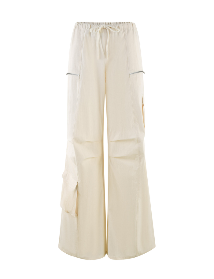 The TIGERMIST HERMIONE PANT in Soft Butter features a wide-leg, baggy cargo style with an elastic drawstring waist, zippered side pockets, and large leg flap pockets, showcased on a plain white background.