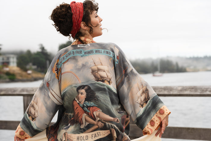 Model wearing the Hold Fast Pixie Duster featuring a Victorian woman rowing through a storm, seagulls, and rainbow horizon – Market of Stars.