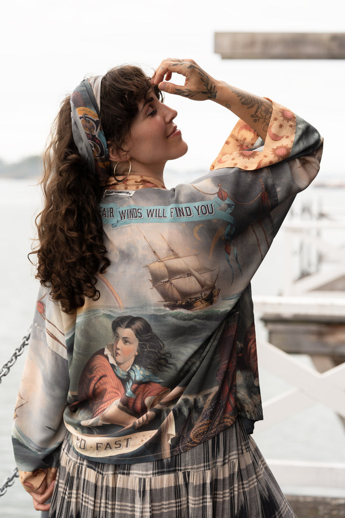 Model wearing the Hold Fast Pixie Duster featuring a Victorian woman rowing through a storm, seagulls, and rainbow horizon – Market of Stars.
