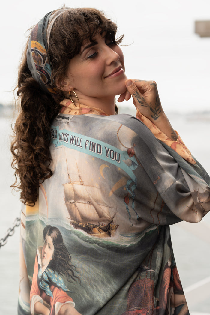 Model wearing the Hold Fast Pixie Duster featuring a Victorian woman rowing through a storm, seagulls, and rainbow horizon – Market of Stars.
