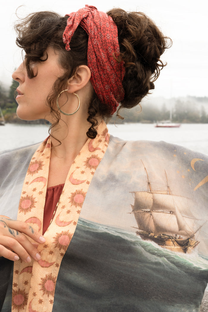 Model wearing the Hold Fast Pixie Duster featuring a Victorian woman rowing through a storm, seagulls, and rainbow horizon – Market of Stars.