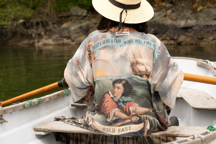Model wearing the Hold Fast Pixie Duster featuring a Victorian woman rowing through a storm, seagulls, and rainbow horizon – Market of Stars.