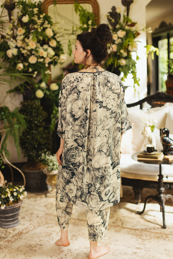 Model wearing a knee-length shift dress featuring black-and-ivory floral lithographs from the 1900's - Market of Stars