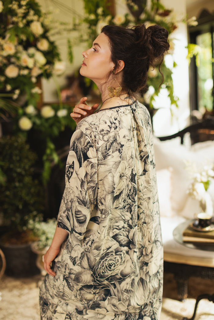 Model wearing a knee-length shift dress featuring black-and-ivory floral lithographs from the 1900's - Market of Stars