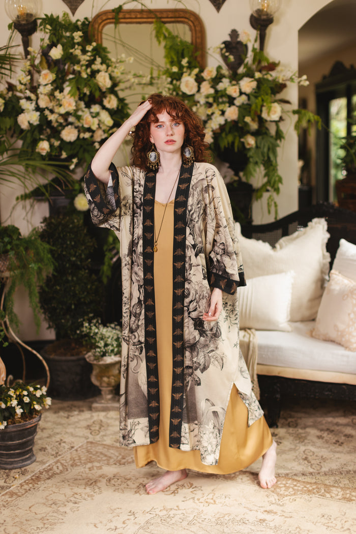 Model wearing a full-length opera duster featuring black-and-ivory floral lithographs from the 1900's - Market of Stars