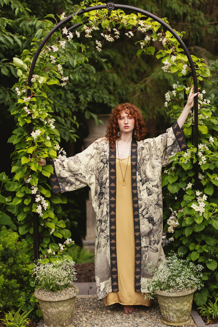 Model wearing a full-length opera duster featuring black-and-ivory floral lithographs from the 1900's - Market of Stars