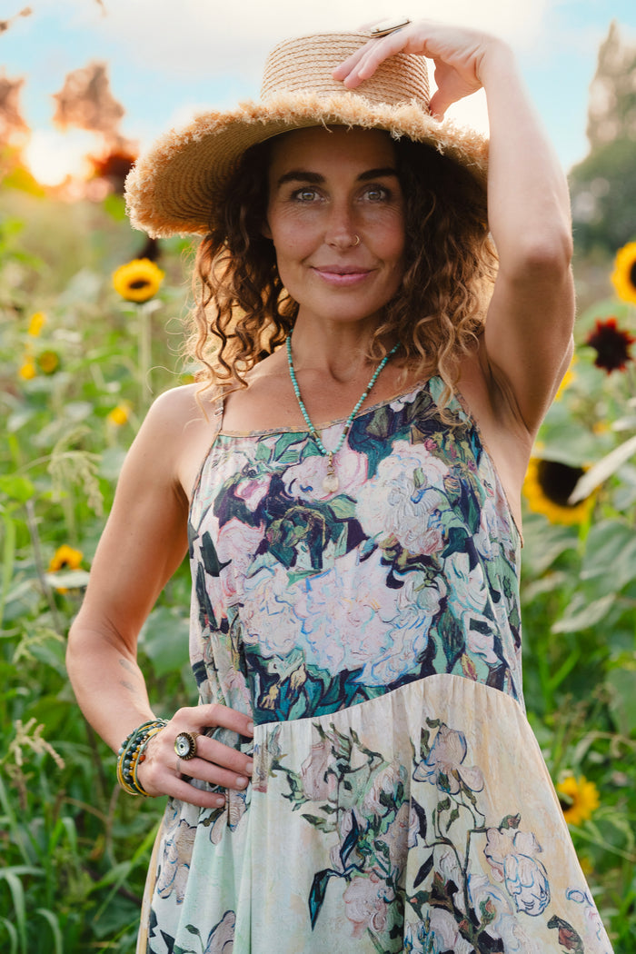 Model wearing bamboo viscose slip dress featuring Van Gogh artwork and quote, with painted blossoms, book, sun, and eye in rich sunny tones of jade and gold - Market of Stars
