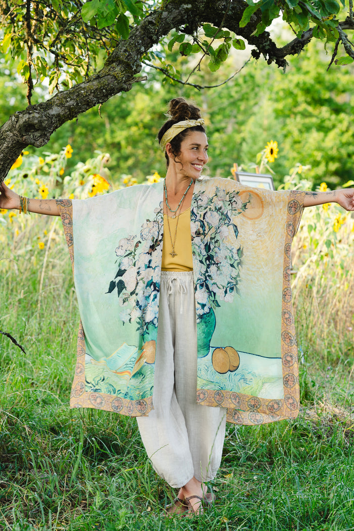 Model wearing mid-length duster featuring Van Gogh artwork and quote, with painted blossoms, book, sun, and eye in rich tones of jade and gold - Market of Stars