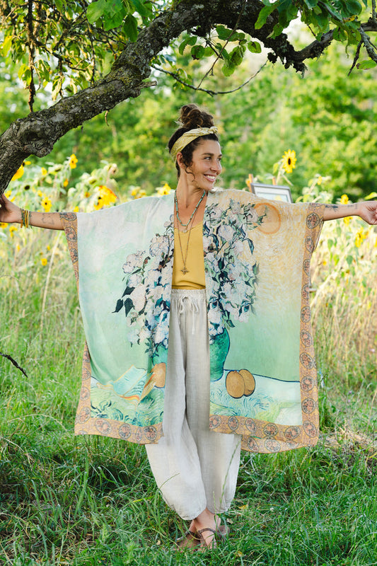 Model wearing mid-length duster featuring Van Gogh artwork and quote, with painted blossoms, book, sun, and eye in rich tones of jade and gold - Market of Stars
