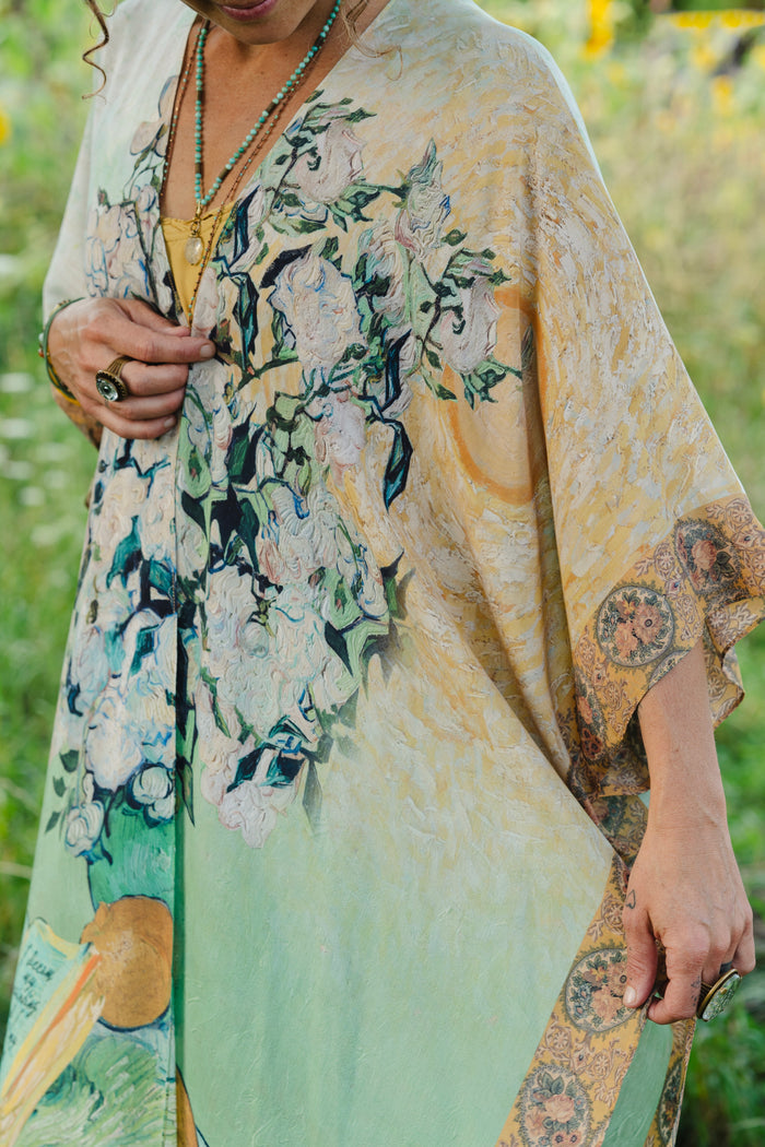 Model wearing mid-length duster featuring Van Gogh artwork and quote, with painted blossoms, book, sun, and eye in rich tones of jade and gold - Market of Stars