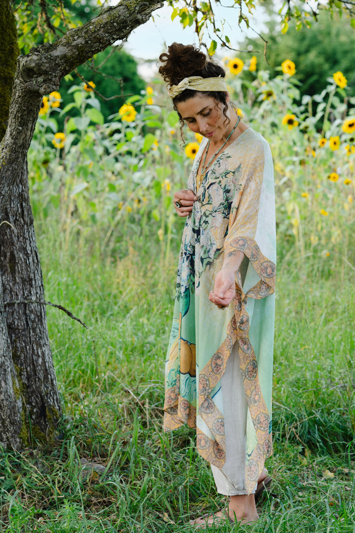 Model wearing mid-length duster featuring Van Gogh artwork and quote, with painted blossoms, book, sun, and eye in rich tones of jade and gold - Market of Stars