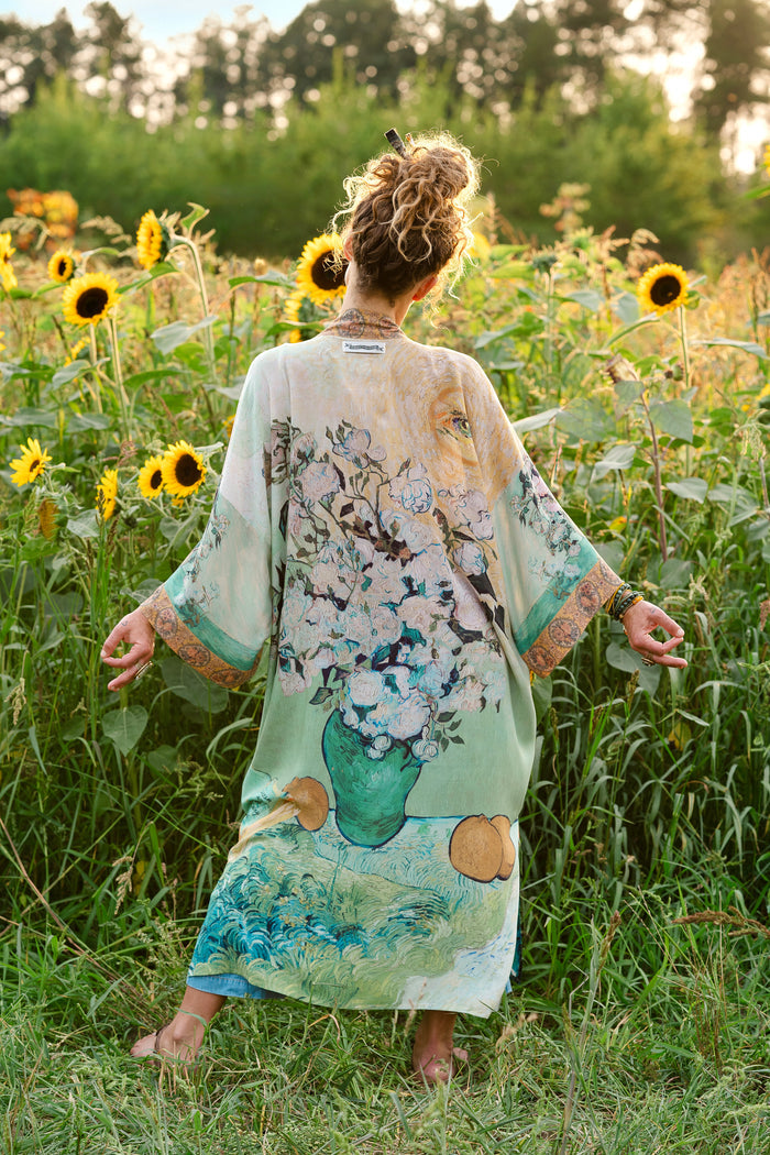 Model wearing long kimono duster featuring Van Gogh artwork and quote, with painted blossoms, book, sun, and eye in rich tones of jade and gold - Market of Stars