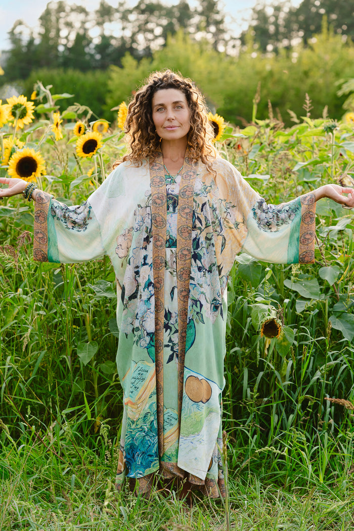 Model wearing long kimono duster featuring Van Gogh artwork and quote, with painted blossoms, book, sun, and eye in rich tones of jade and gold - Market of Stars