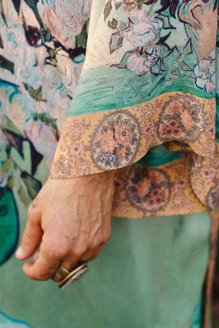 Model wearing long kimono duster featuring Van Gogh artwork and quote, with painted blossoms, book, sun, and eye in rich tones of jade and gold - Market of Stars
