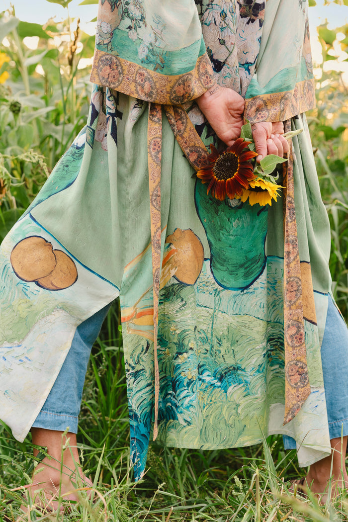 Model wearing long kimono duster featuring Van Gogh artwork and quote, with painted blossoms, book, sun, and eye in rich tones of jade and gold - Market of Stars