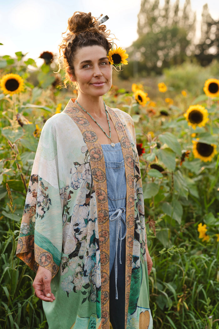Model wearing long kimono duster featuring Van Gogh artwork and quote, with painted blossoms, book, sun, and eye in rich tones of jade and gold - Market of Stars
