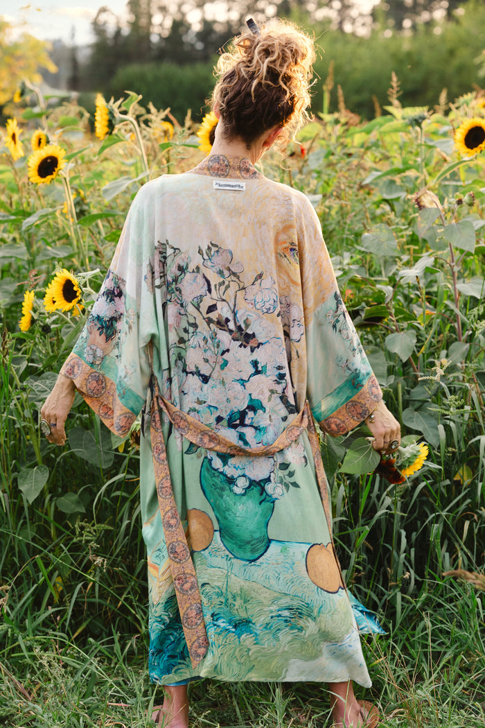 Model wearing long kimono duster featuring Van Gogh artwork and quote, with painted blossoms, book, sun, and eye in rich tones of jade and gold - Market of Stars