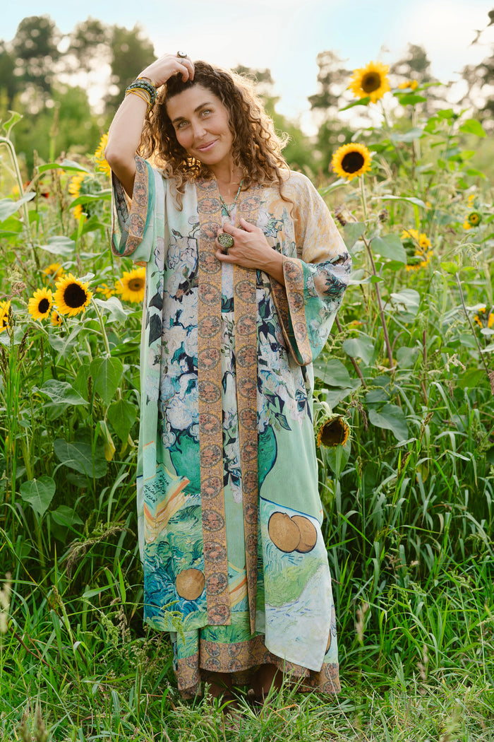 Model wearing long kimono duster featuring Van Gogh artwork and quote, with painted blossoms, book, sun, and eye in rich tones of jade and gold - Market of Stars