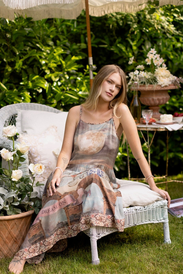 Model wearing the Imaginarium Bohéme Slip Dress featuring a dreamy layered print of historic landscapes, chandeliers, and a sleeping muse – Market of Stars.