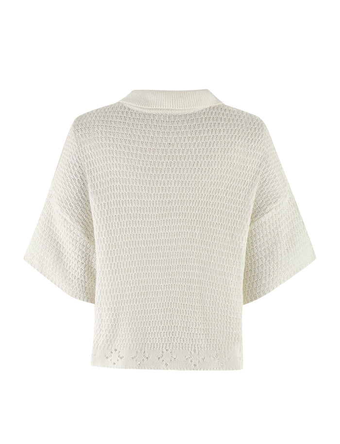 A back view of the JANAI TOP - WHITE : CREAM by TIGERMIST, showcasing its short, wide sleeves and textured, slightly open-weave crochet pattern. The top features an oversized fit and a ribbed collar, enhancing its relaxed appeal.