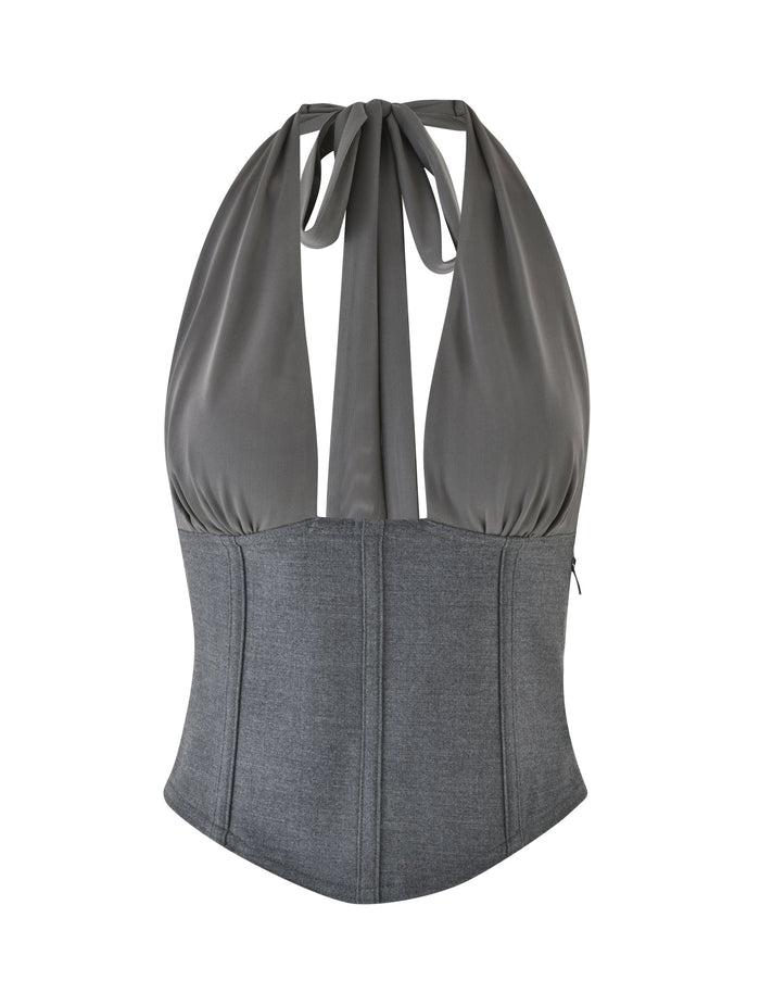 The JANECE TOP - GREY by TIGERMIST features a sophisticated gray suiting fabric crafted into a halter neck design. The garment includes gathered material for added elegance, complemented by a wide band at the bottom for a structured, corset-like look, and is finished with a plunging neckline for a contemporary edge.