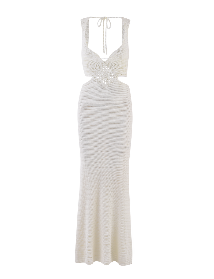 The JONAH MAXI DRESS by TIGERMIST is a cream sleeveless crochet maxi with a fitted bodice, open back, neck tie detail, and a subtly flared hem featuring an elegant diamond pattern.