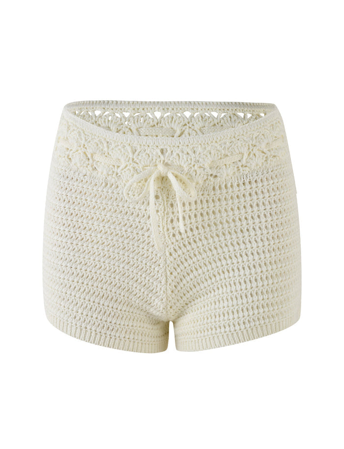 The JONAS SHORT - WHITE : CREAM by TIGERMIST showcases crocheted cream-colored shorts with a delicate floral pattern at the waistband, a drawstring tie at the front, and intricate contrast stitching. These super mini length shorts offer a handmade, cozy look perfect for any casual outing.