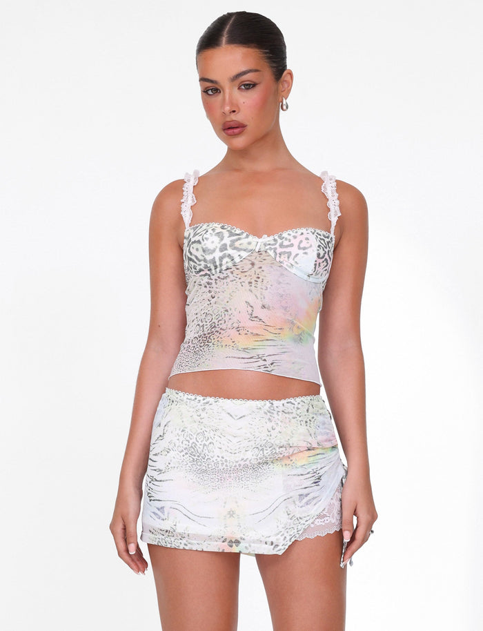 A woman wears the TIGERMIST JOSEPHINE TOP in white animal print with lace straps, paired with a matching mini skirt featuring lace trim, standing against a plain white background.