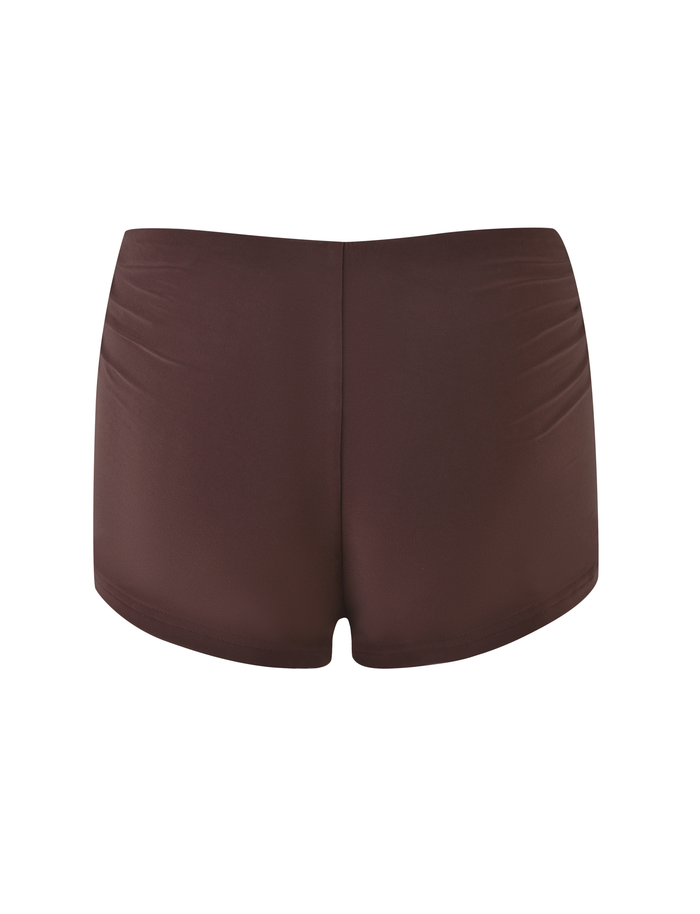 The JOVIENNE SHORT - BROWN: CHOCOLATE by TIGERMIST features chocolate brown jersey swim shorts with a mid-rise waist, smooth fabric, and subtle side ruching, shown from the back against a white background.