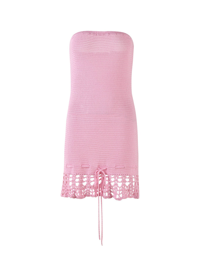 The Julane Dress in Pink from Tigermist is a strapless crochet dress with a form-fitting bodice and a lacy, scalloped hemline. The bottom edge features a decorative drawstring tied in the center, giving it an airy and lightweight appearance perfect for warm weather.