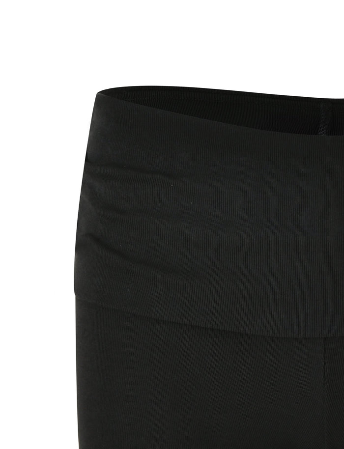 A close-up view of the waistband and upper section of the KARINA RIB SHORT - BLACK from TIGERMIST. The fabric is smooth with a slight stretch, showcasing a low-rise waist design. Visible stitching highlights the curve of the waistband, and no additional details or patterns are present.