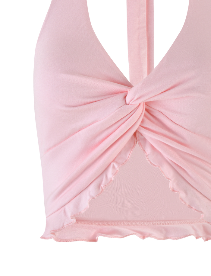A close-up of the TIGERMIST KATYA HALTER TOP in pale pink, showcasing a front twist detail and a ruffled hem.
