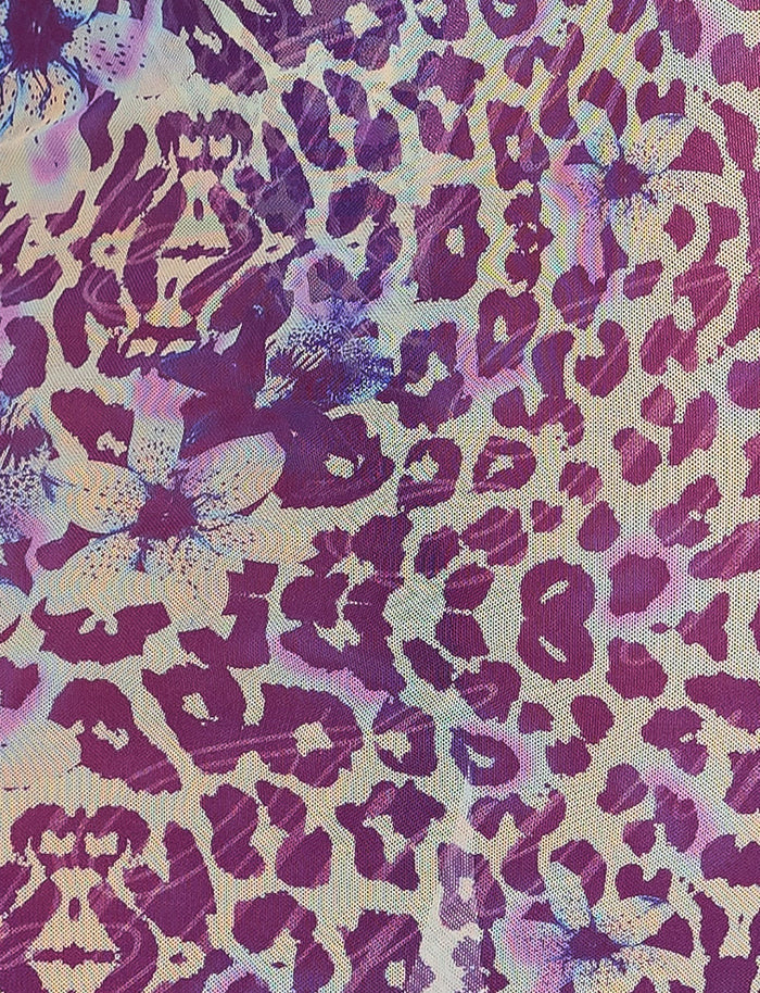 The KELLAN SKIRT - PURPLE by TIGERMIST showcases a vibrant, multicolored pattern with shades of purple, pink, and blue. It features a mix of abstract leopard spots and floral designs set against a background that alternates between light and deep hues, creating a dynamic visual effect reminiscent of Tiger Mist aesthetics.