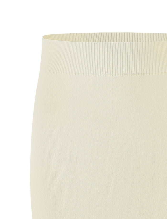A close-up view of the LEDGER SKIRT - WHITE : CREAM from TIGERMIST showcases a light cream-colored, ribbed, high-waisted elastic waistband. The texture and stretchiness of the fabric are clearly visible, emphasizing the snug fit and smooth surface.