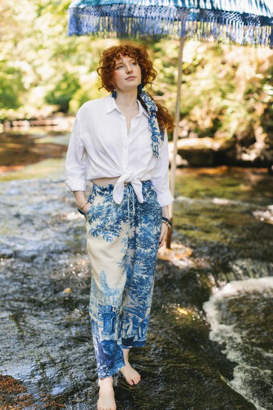 Model wearing Let the Light In linen Artist Pant featuring print of Delft blue and white landscape pottery, and positive message of light and hope - Market of Stars
