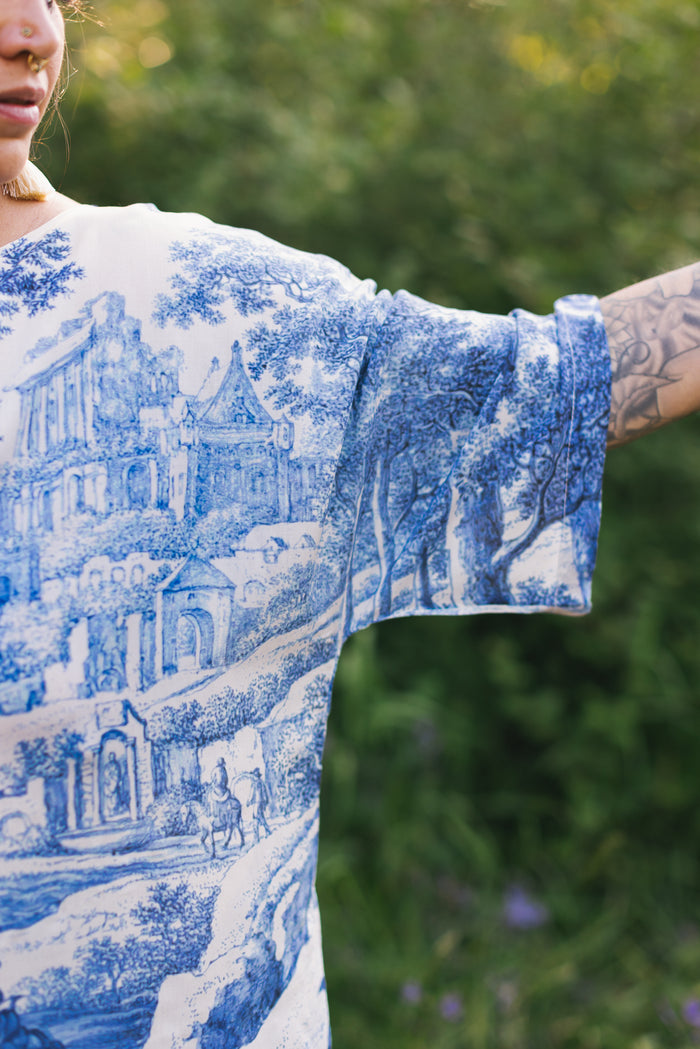 Model wearing Let the Light In bamboo viscose Luxe Tee shirt featuring print of Delft blue and white landscape pottery, and positive message of light and hope - Market of Stars